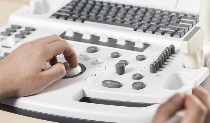Cardiologist adjusting controls on an echocardiogram machine with ultrasound probe nearby